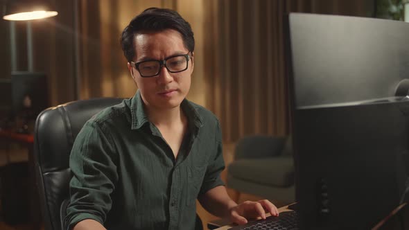 Asian Male Drinking Coffee While Works On His Personal Computer With Big Display