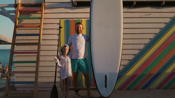 Summer vacation. Happy father and daughter posing with sup board.