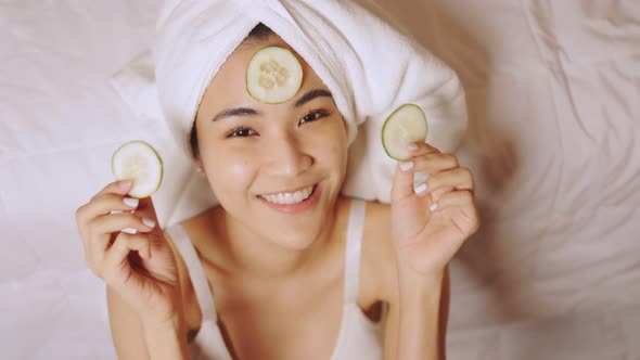 Happy attractive asian woman apply skincare cream on face and body.