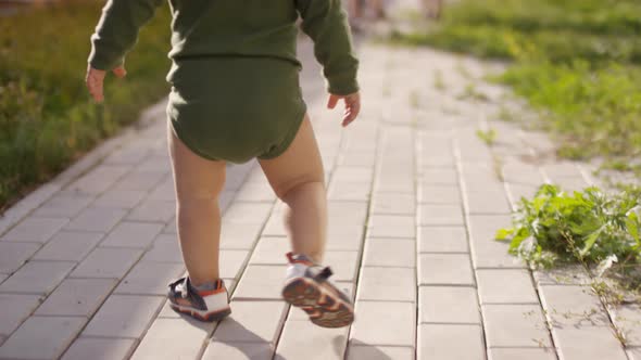 Legs of Unrecognizable Toddler Walking on Footpath in Garden