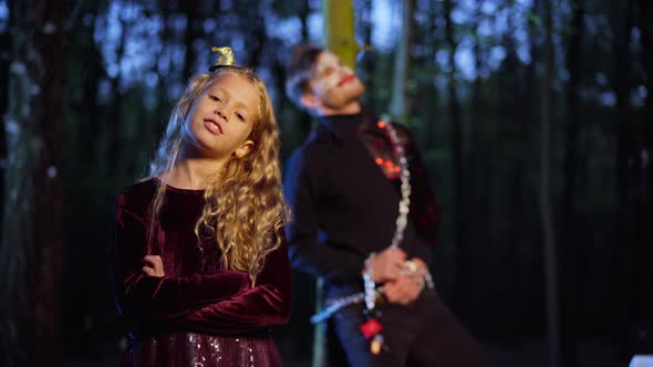 Portrait of Proud Cute Caucasian Girl Standing with Crossed Hands Looking at Camera in Dark Forest