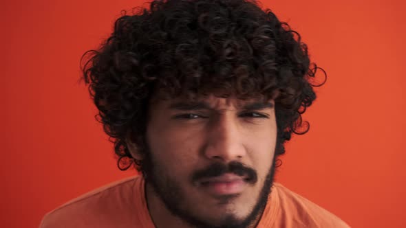 Serious curly-haired Indian man peering at the camera