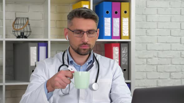 Doctor listens patient online video call laptop webcam, drinking coffee tea