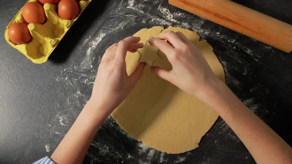 Hands Rolling and Cutting Dough on Table