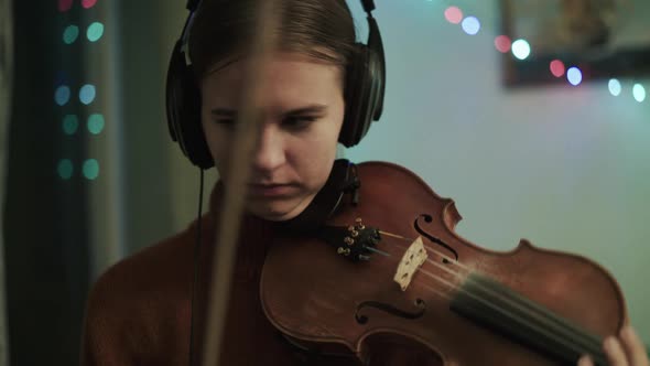 Young Woman Rehearsing the Instrumental Melody with Violin Using Headphones