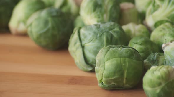 Slow Motion Panning Left to Right Across Fresh Green Brussels Sprouts on Wooden Tabletop