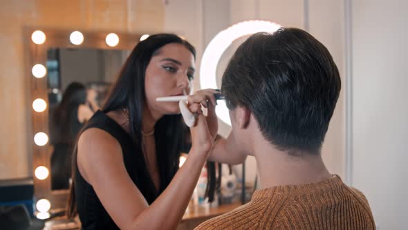 Woman Make Up Artist Applying Highlight Shades on a Face of Male Model Using a Brush