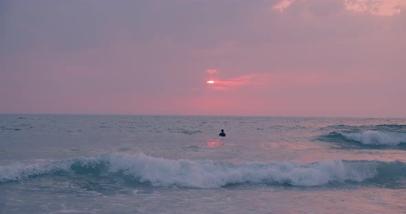 Young People in Wetsuit Surf on Sunset Beach