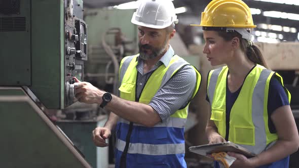 Male engineer foreman training and explain machine controlling to female trainee