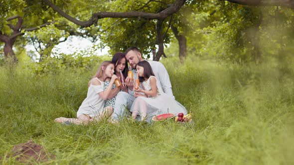 Portrait of Caucasian Parents with Two Cute Daughters Drinking Juice in Glass