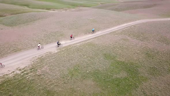 A Group of Cyclists Rides Along the Windmills