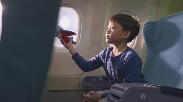 Asian young little boy playing aircraft model toy, sitting on airplane and wants to be a pilot.