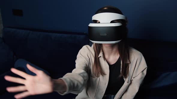 Young Caucasian Woman Wearing VR Helmet Making Hands Gesture at Home. Attractive Woman Enjoying