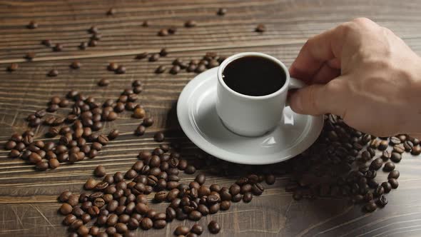 Male Hand Takes a Mug of coffee, Coffee Cup and Coffee Beans. White Cup of Steaming Coffee