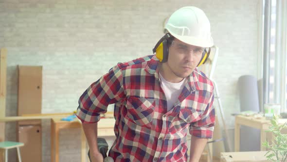Portrait of a Skilled Professional Man with a Drill in His Hands and a Helmet