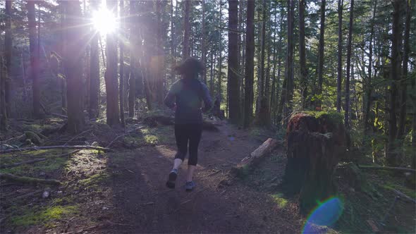 Caucasian Woman Trail Running in the Green Forest