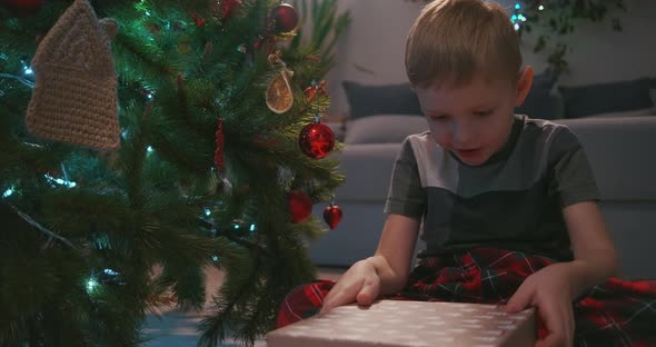 Happy Smiling Little Boy Opens His Christmas Gift From Santa Claus