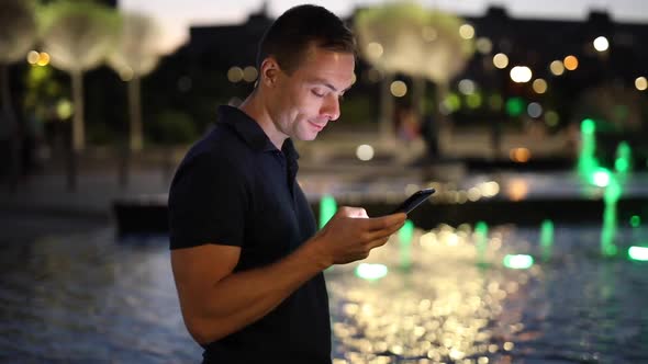 Man Using Mobile Phone Standing Near Fountain