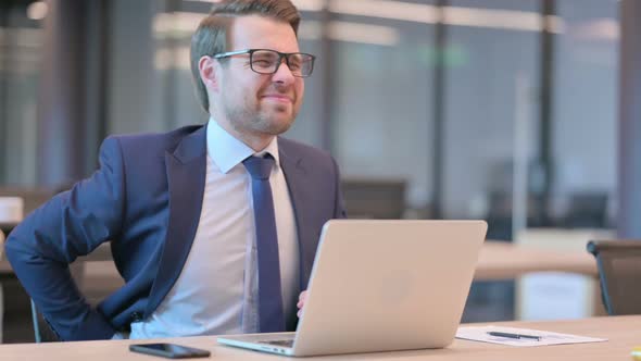 Businessman with Laptop having Back Pain in Office