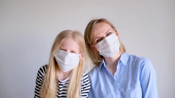 Happy Blonde Mother and Daughter Wearing Surgical Medical Face Mask Against Infectious Disease