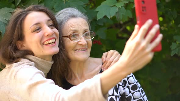 Adult Daughter and Senior Mum are Taking Selfportrait Picture Selfie on Red Smartphone Together