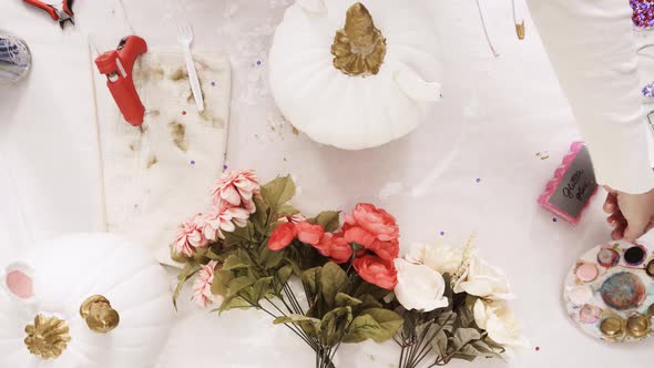 Top view. Mother and daughter decorating craft pumpkins with flowers to make an unicorn theme pumpki