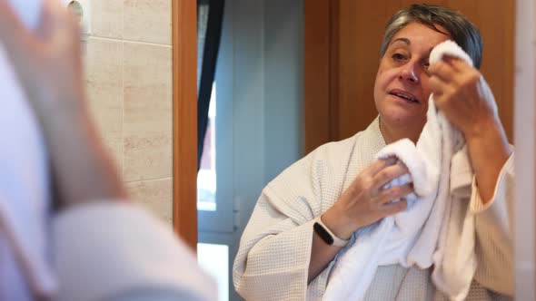 Woman wiping face in bathroom