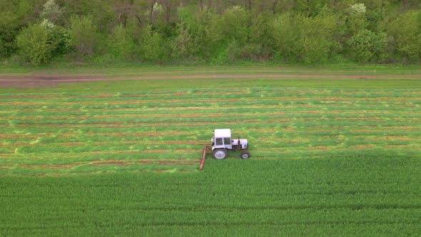 Mowing with a Agriculture Machine Tractor with Mowers on the Big Farm Field