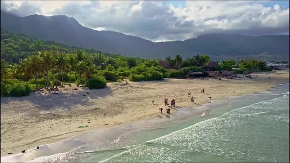 Drone Flies Over People Searching on Sand Beach Edge