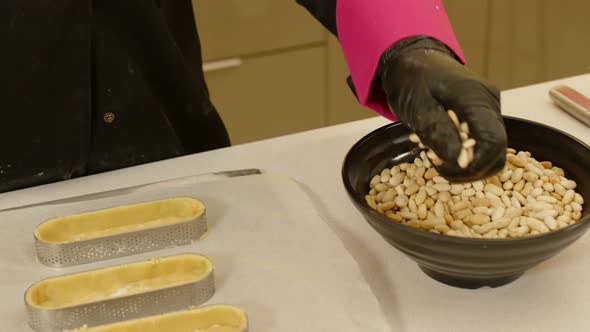 Hands filling tartlets with loubia. Close up, gimbal