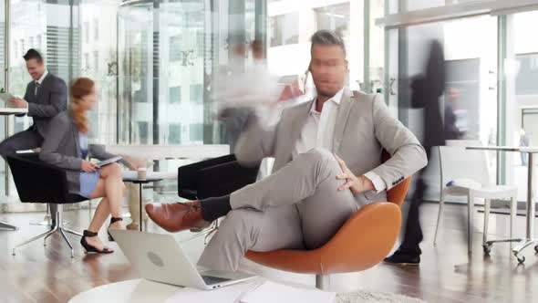 Time-lapse of businessman talking on mobile phone while using laptop