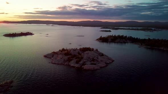 Rocky Granite Islands with Green Pine Trees in Blue Lake at Sunset, Drone Aerial Wide Dolly In. Flyi