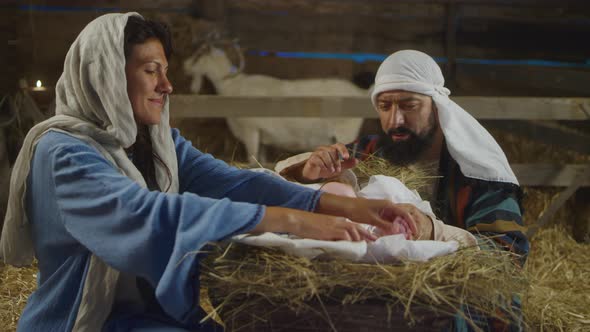 Mary and Joseph Taking Care of Baby Jesus in Inn Stable