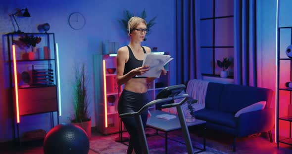 Woman in Headset Talking Into Mic when Reading Documents During Exercising on Treadmill at Home