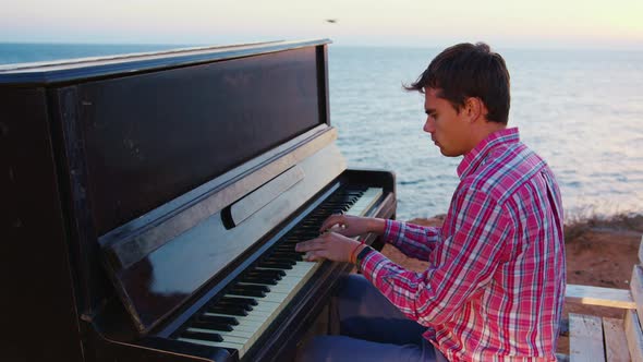 Young Man Playing Melody on Piano on Seashore