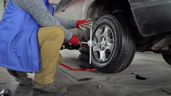 Worker unscrew the wheel from the car