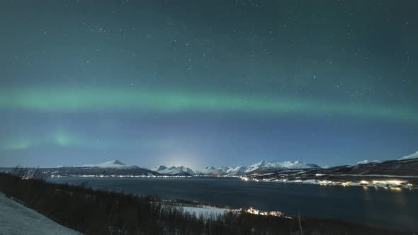 Green Northern Lights and Snowy Mountains at Winter Night. Troms, Norway