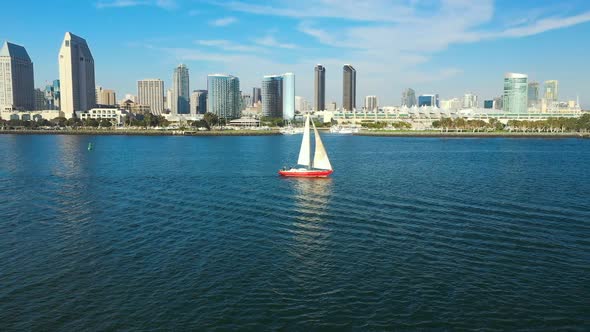 Red sailboat on the San Diego Bay with a view of San Diego's skyline