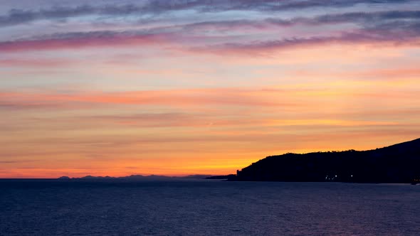 Sunset timelapse over city of Sanremo and France in background. Italian and French coastline. Day to