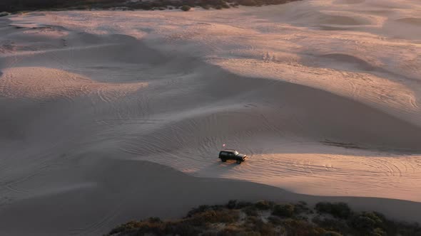 Drone Footage of Picturesque Sand Field Within Barren Landscape Lit By the Sun