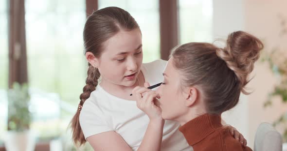 Teen Girl is Learning to Apply Make Up to Her Mother She Applies the Eyshadows on the Eyelids of