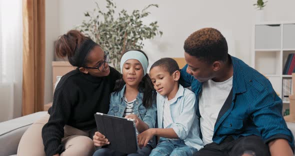 The Family Spends Time Together on the Couch the Parents with Their Two Children Browse the