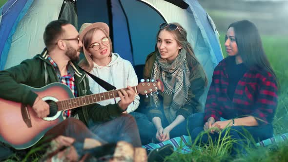 Joyful Friends Sitting Campfire Playing Guitar Singing Song at Sunset