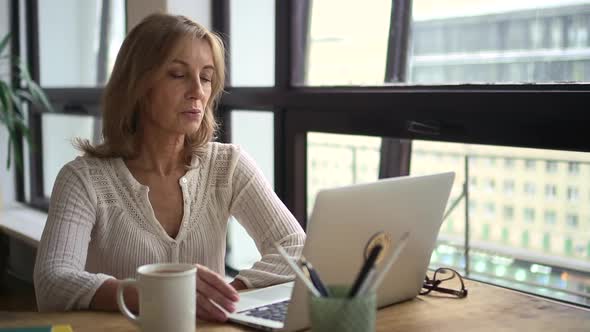 Businesswoman Having Online Talk in Front of Laptop Screen and Sitting at Table in Home Office