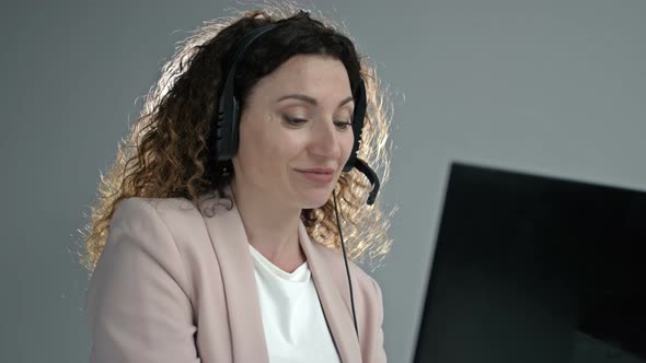 Customer Support Agent or Call Center with Headset Works on Desktop Computer While Supporting the