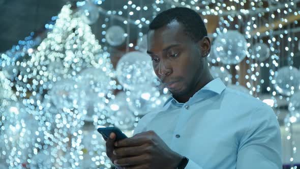 An African American Man Uses a Smartphone To Communicate on the Internet.