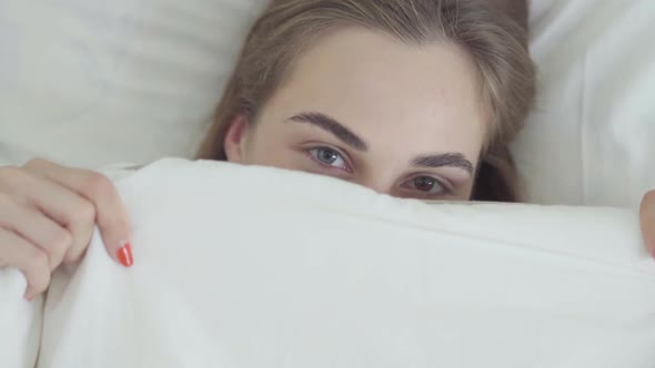 Portrait Cute Young Happy Caucasian Woman with Different Colored Eyes Lying in Bed in the Morning