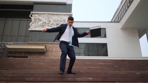 Happy Successful Businessman Playfully Descends Stairs Near Office Building