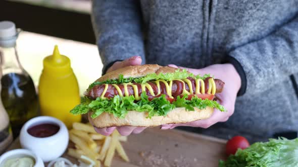 Woman Holding Fresh Made Hotdog with Mustard and Ketchup Outdoors
