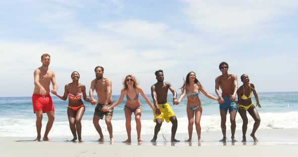 Front view of mixed-race friends jumping together on the beach 4k